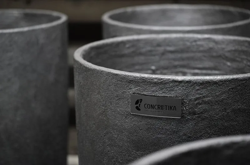 Крупный план бетонных кашпо CONCRETIKA с фирменным шильдиком, видна фактура бетона